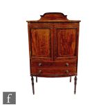 An Edwardian inlaid bowfront mahogany music cabinet enclosed by a pair of doors above two drawers,