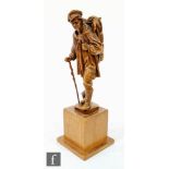 A 20th Century carved Black Forest walnut figure of a poacher smoking a pipe and carrying dead game,