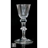 An 18th Century drinking glass circa 1740, the round funnel bowl above a flattened shoulder knop and