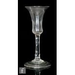 An 18th Century wine glass circa 1740, the waisted bell bowl above a plain stem, raised to a domed