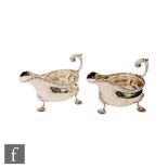 A pair of hallmarked silver sauce boats of plain form, each raised on three pad feet with gadroon