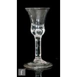 An 18th Century drinking glass, the waisted bell bowl with a tear in solid base, above a plain