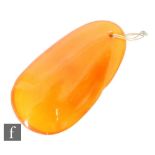 An early 20th Century butterscotch amber pendant of compressed oval form, length 6cm, weight 16.5g.