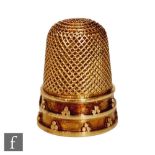 A small gold thimble decorated with two bands each with dot patterns, unmarked, tested as 18ct.