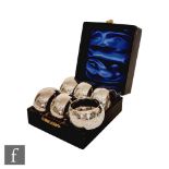 A cased set of six hallmarked silver circular napkin rings with part engraved foliate decoration,