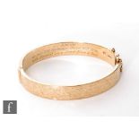 A 9ct hallmarked hinged bangle with foliate engraving to front and presentation engraving to