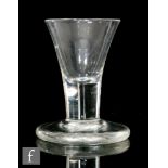 An 18th Century firing glass circa 1740, the funnel bowl above a short plain stem and raised to a