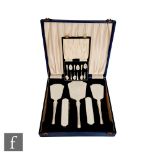 A cased hallmarked silver five piece brush set, each with white enamel decoration to back, with a