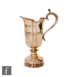 A hallmarked silver pedestal helmet cream jug of plain form with knop stem and scroll handle, height