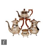 A hallmarked silver tea, coffee and hot water pot, each of faceted form and raised on four scroll