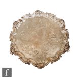 A hallmarked silver circular salver with engraved foliate scroll decoration within scalloped and