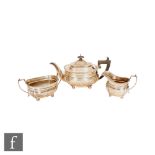 A hallmarked silver three piece boat shaped tea set of plain form with gadroon borders and raised on