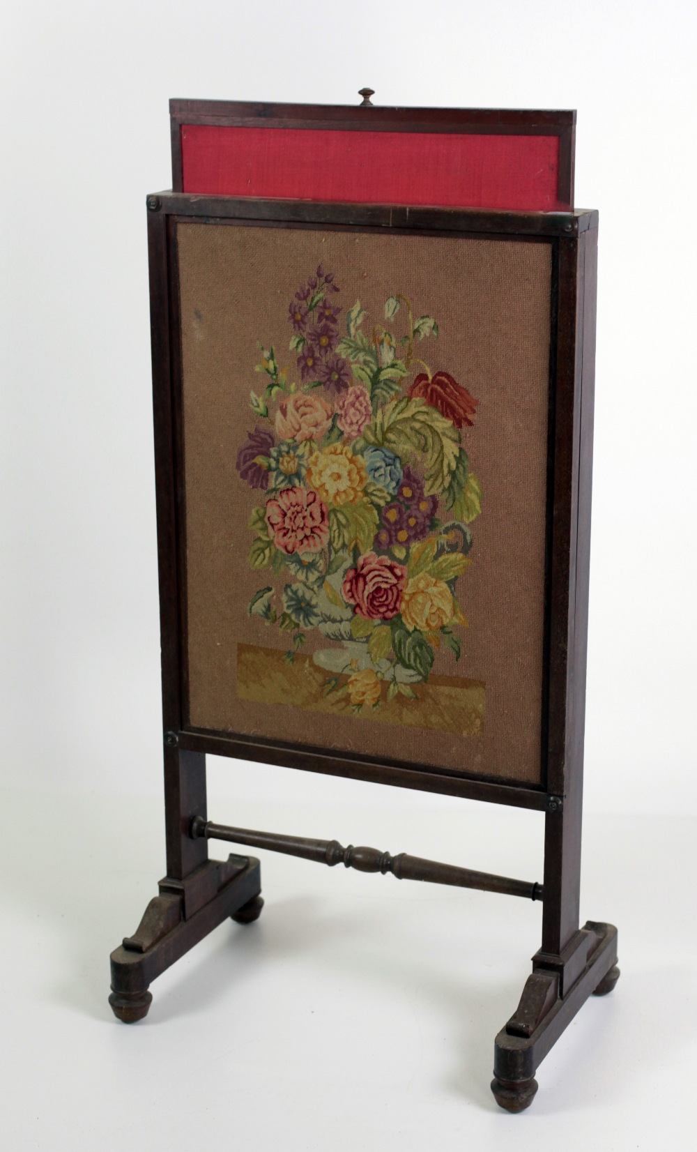 A Victorian mahogany Firescreen, with floral needlework panel on outsplayed legs.