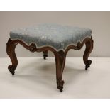 A Victorian walnut Stool, in blue fabric, on carved cabriole legs.