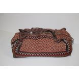 An original large Arabian leather bound wool worked Camp Bag, with decorated panels,