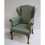 A Georgian style wing back Armchair, covered in green leatherette on front cabriole legs.
