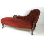 A Victorian carved walnut Chaise Longue, with deep buttoned back, covered in rust coloured draylon.