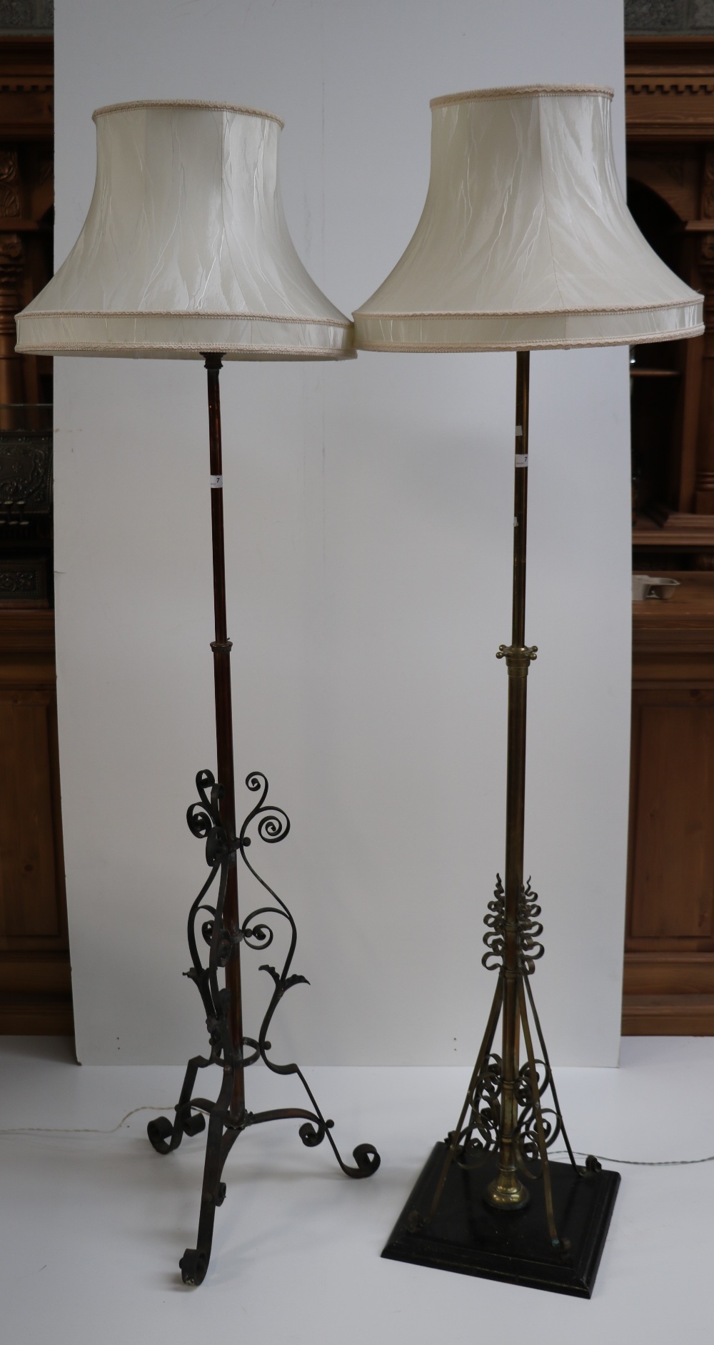 Two similar brass lamp Standards, with decoration in steel design, with cream shades.
