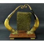 An Edwardian brass Gong, supported by two brass mounted cows horns, on an oak stand with brass feet.