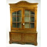 A Continental walnut framed Bookcase, the arched moulded cornice above a plain frieze,