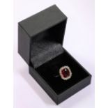 An attractive Ladies gold Ring, with large ruby type inset stone surrounded by 18 cut diamonds.