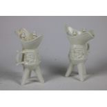 A pair of Chinese Blanc-de-Chine porcelain Wine Vessels (JUE) each with three legs supporting a