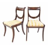 Pair of Regency mahogany dining chairs with carved reeded splats over drop-in seats and upon sabre