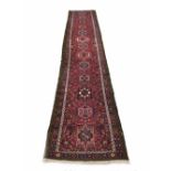 Persian red ground runner, decorated with thirteen differing medallions within dense floral