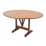 Antique French stained Vendage table, the oval plank tilt top over trestle supports, 56" across, 28"