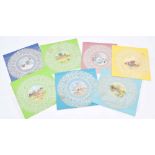 Set of seven painted circular lace coaster mats, centrally decorated with seasonal pastoral