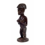 20th century Lwena carved figure of a lady, with angular coiffure, standing on a circular base, 10.