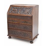 Good early 18th century carved oak bureau, the fall front deeply carved with bacchanalian putti