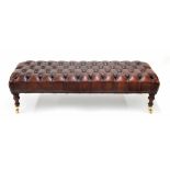 Good leather button upholstered hearth stool/window seat, raised on turned supports terminating in