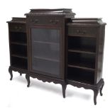 Carved mahogany breakfront bookcase, the caddy tops over frieze drawers above open shelved sections,