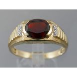 9ct gentleman's signet ring with a central oval cut garnet, approx 2.0ct, flanked by two small