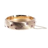 9ct yellow gold ruby set hinged bangle with safety chain, Birmingham 1964, band width 18mm, 33.8gm