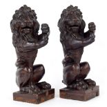 Pair of carved oak lions, each modelled on hind legs as if to hold a banner or flag upon on square