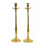 Pair of Arts & Crafts style tall brass candlesticks, the sconces over drip pans supported upon