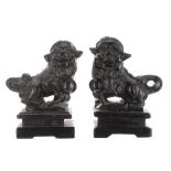 Pair of Chinese carved dark hardstone figures of Buddhistic lions, upon rectangular plinth bases,