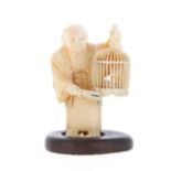 Japanese ivory netsuke modelled as a man holding a birdcage, signed, Meiji, mounted up on a later