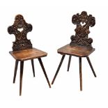 Two similar antique Swiss hall chairs, the shaped backs carved as grotesques with open heart