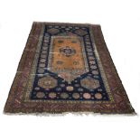 Antique Persian patterned navy ground carpet, decorated with central shield among flower head