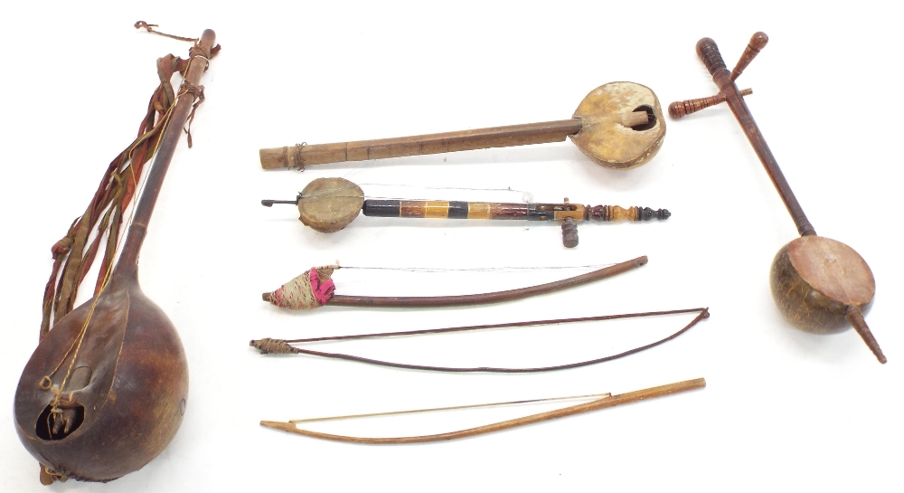 Four various antique and later African and other folk fiddles; together with three various folk
