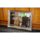 A Modern Gilt Framed Bevelled Mirror broad swept frame. Measures 29 by 42 inches.