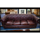 A Large Four Seater Chesterfield Sofa in antique burgundy red leather with button back finish to