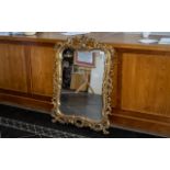 Gilt and Gesso Carved Wood Mirror with a Shaped Bevel Edge, The Frame In The Rococo Style,