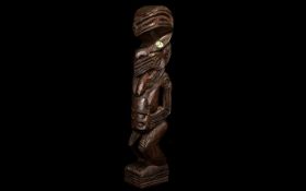 Carved Maori Figure of typical form, Tiki with mother of pearl eyes, 14 inches high.