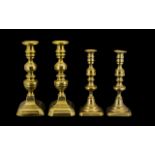 Two Pairs of Antique Brass Candlesticks of typical form, on rectangular canted bases.