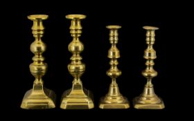 Two Pairs of Antique Brass Candlesticks of typical form, on rectangular canted bases.