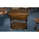 An Ercol Elm Tea Trolley with flat sides on castor feet. The trolley measuring 18 inches wide by